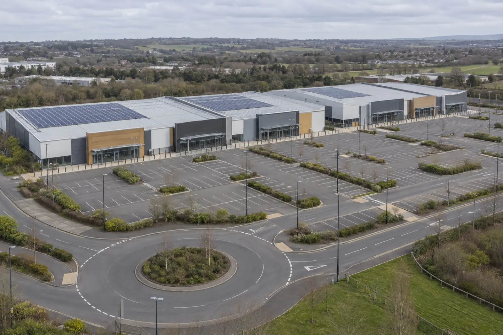 Aerial view of an out-of-town retail park where some of the large unit roofs carry solar arrays and others are bare